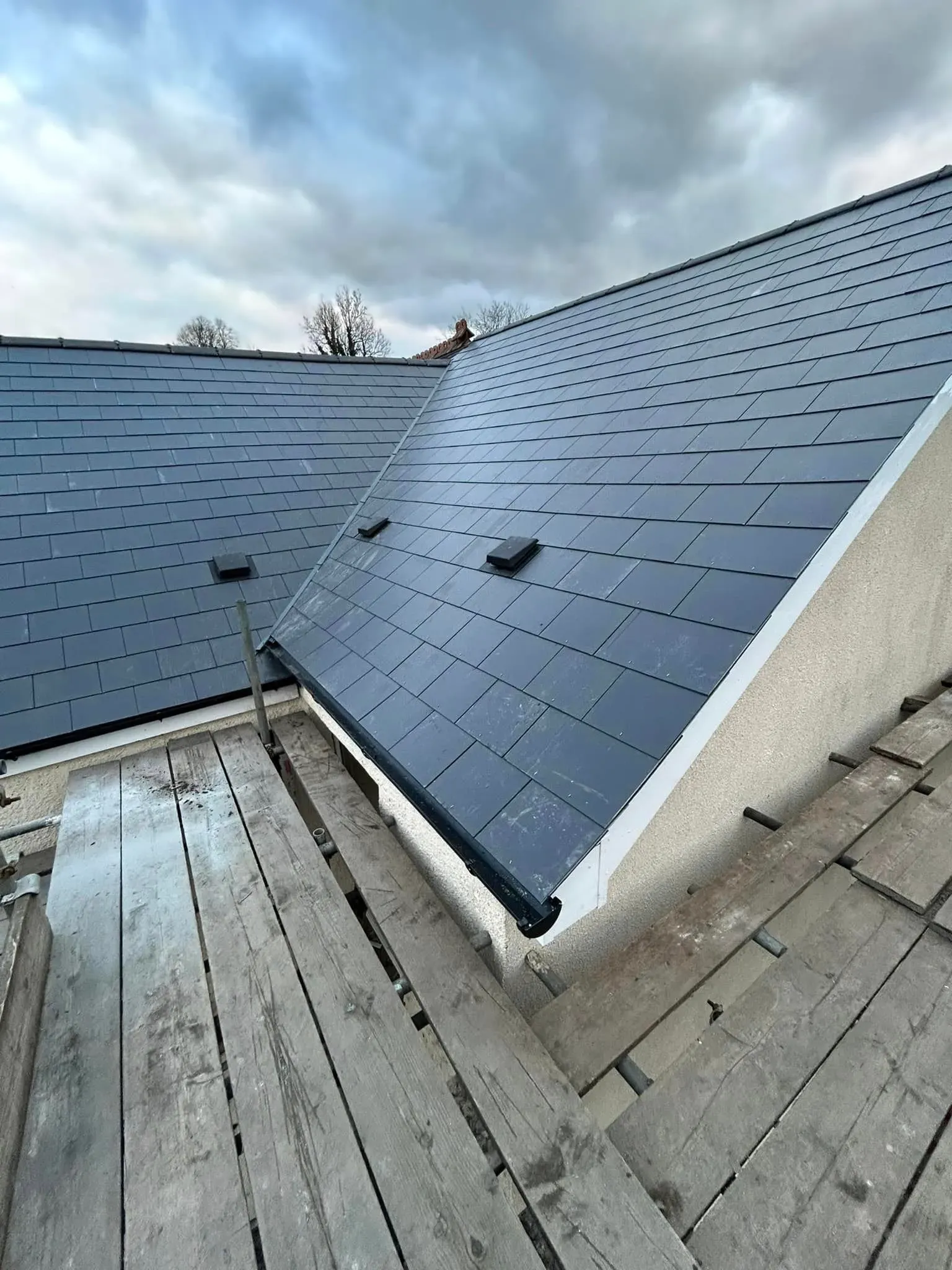 Newly installed tiled pitched roof with scaffolding during construction.