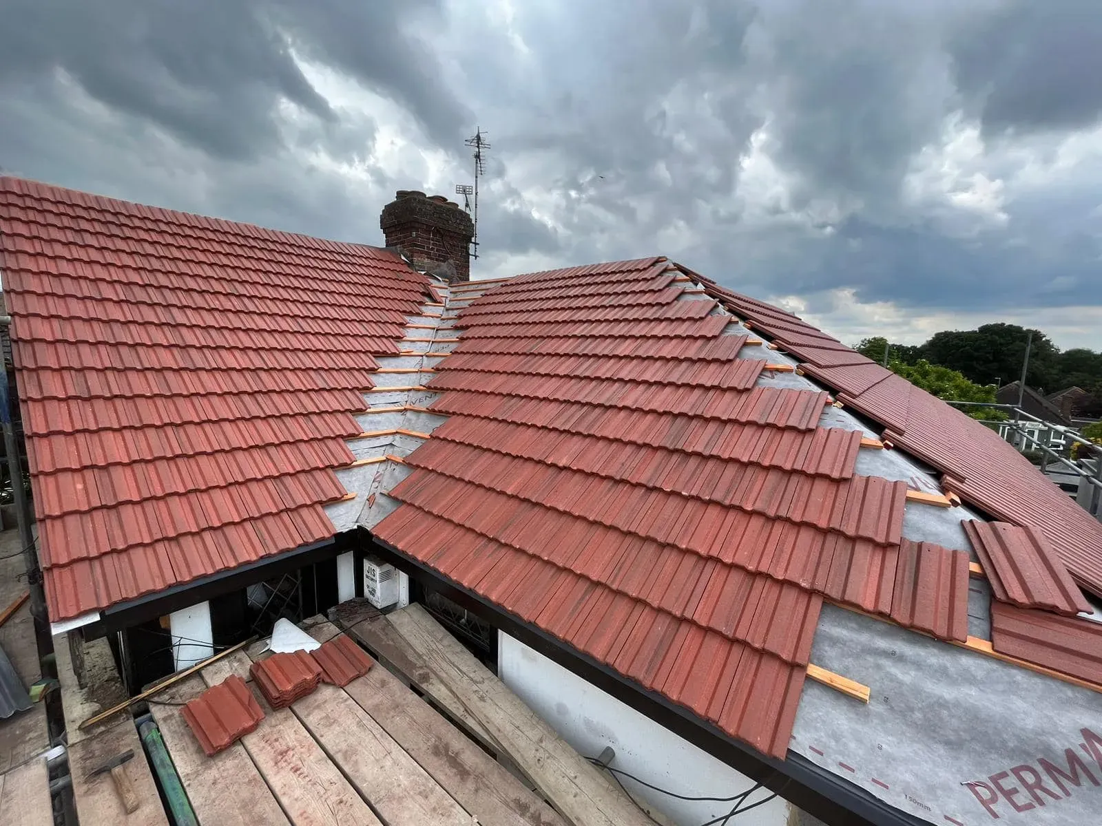 New red roof tiles being installed on a pitched roof